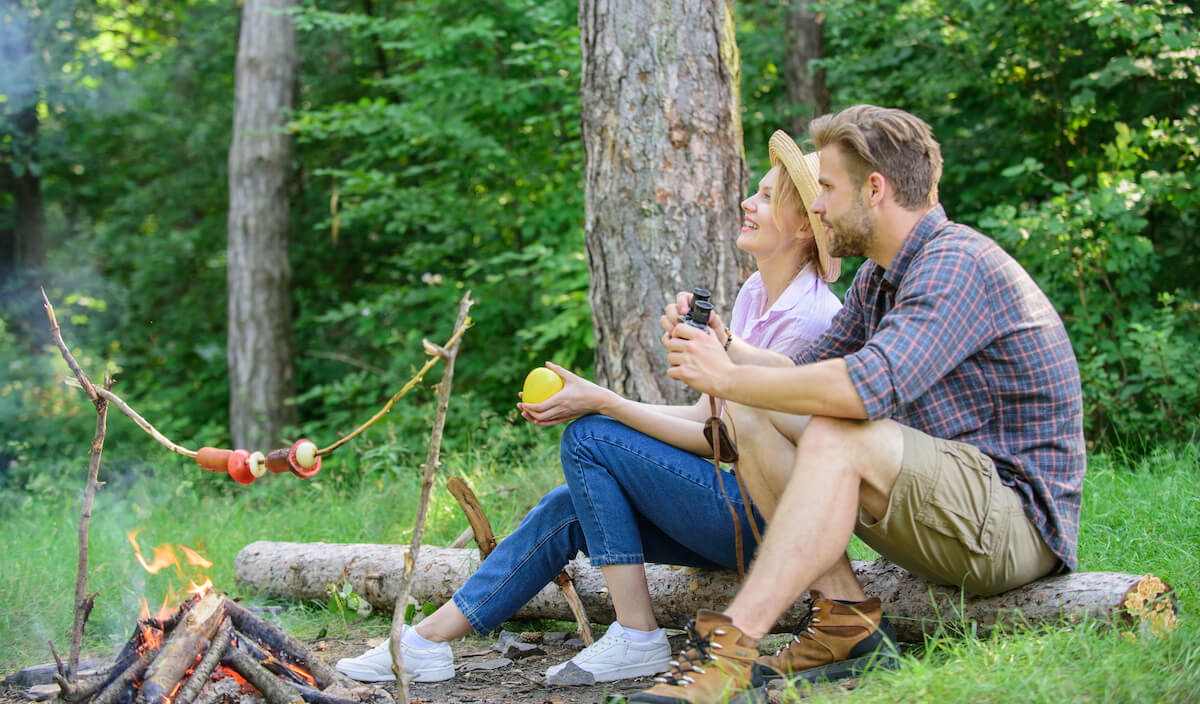 man and woman sitting near a campfire admiring the scenery