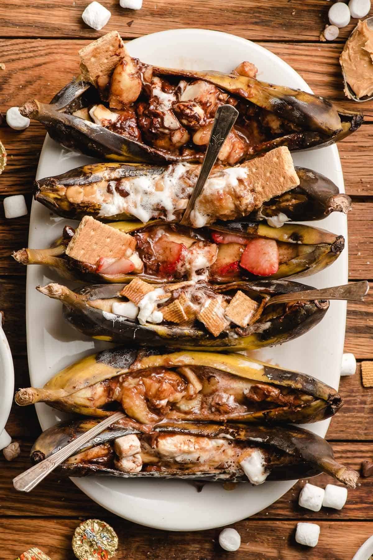 longe plate filled with campfire banana boats with scattered mini marshmallows on table.
