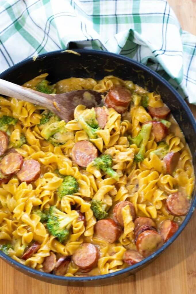one pot cheesy broccoli sausage pasta in a skillet with tea towel in background.