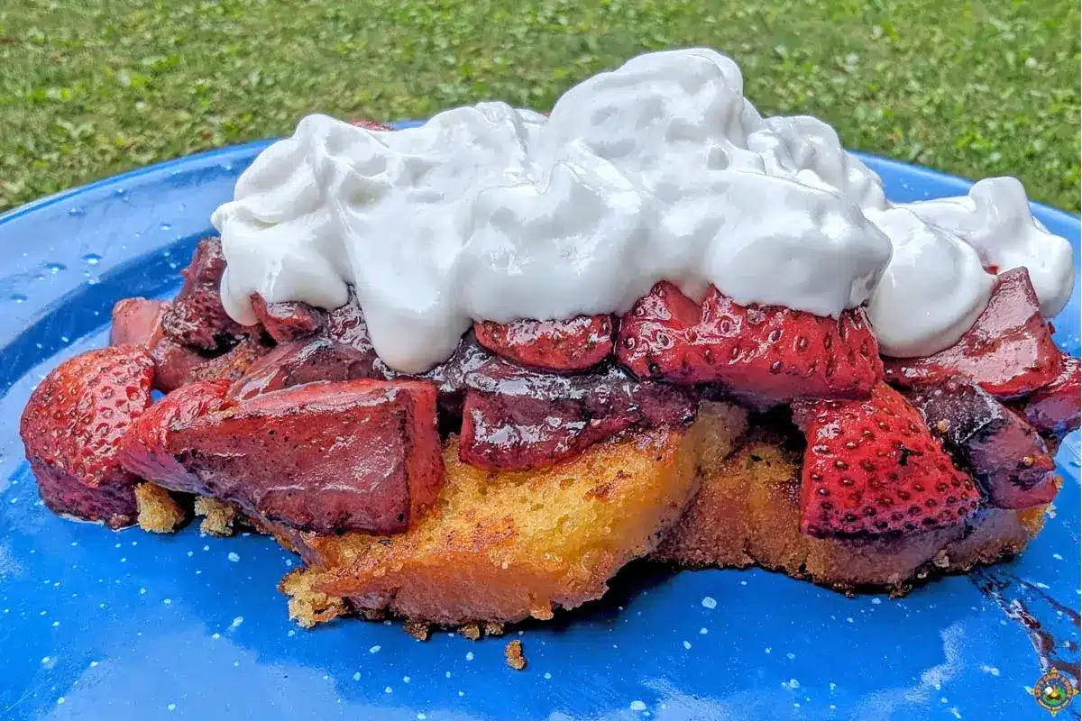 strawberry shortcake dessert with whipped cream on a blue plate.