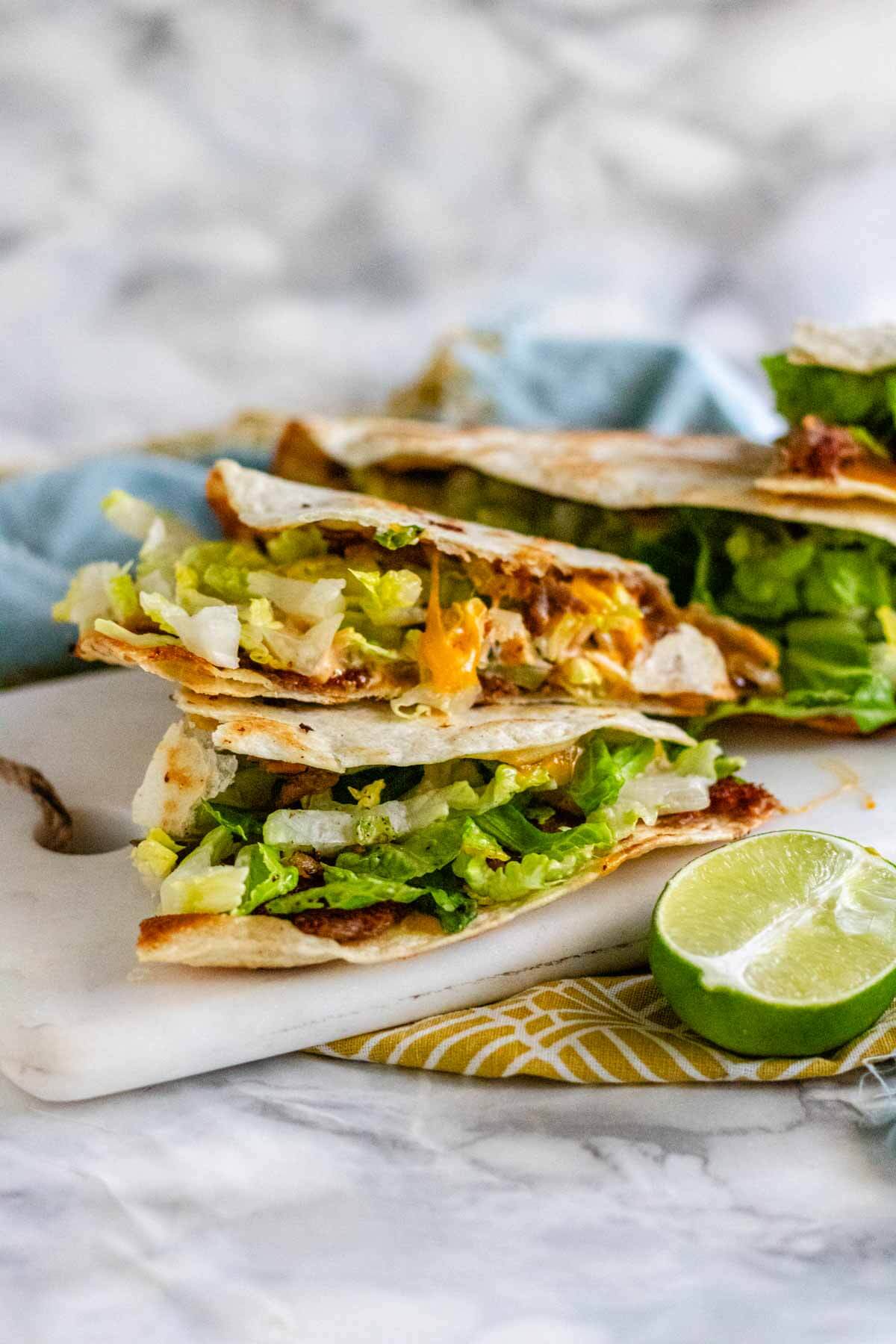 big mac quesadillas on a serving board with half a lime.