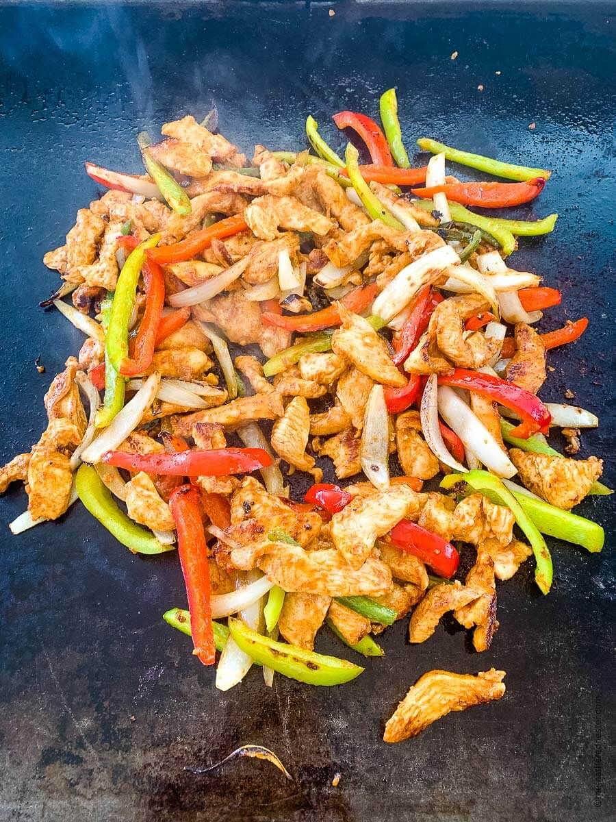 close up of chicken fajita ingredients on griddle plate.