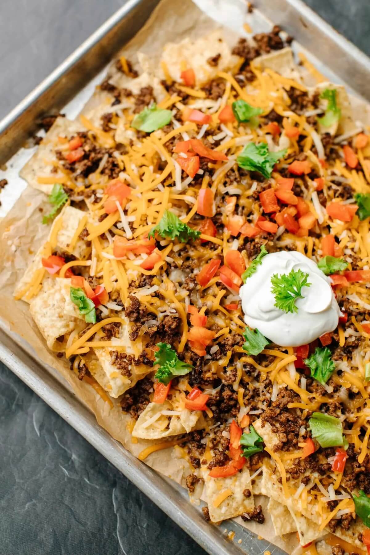 blackstone nachos on a serving tray with toppings on top.