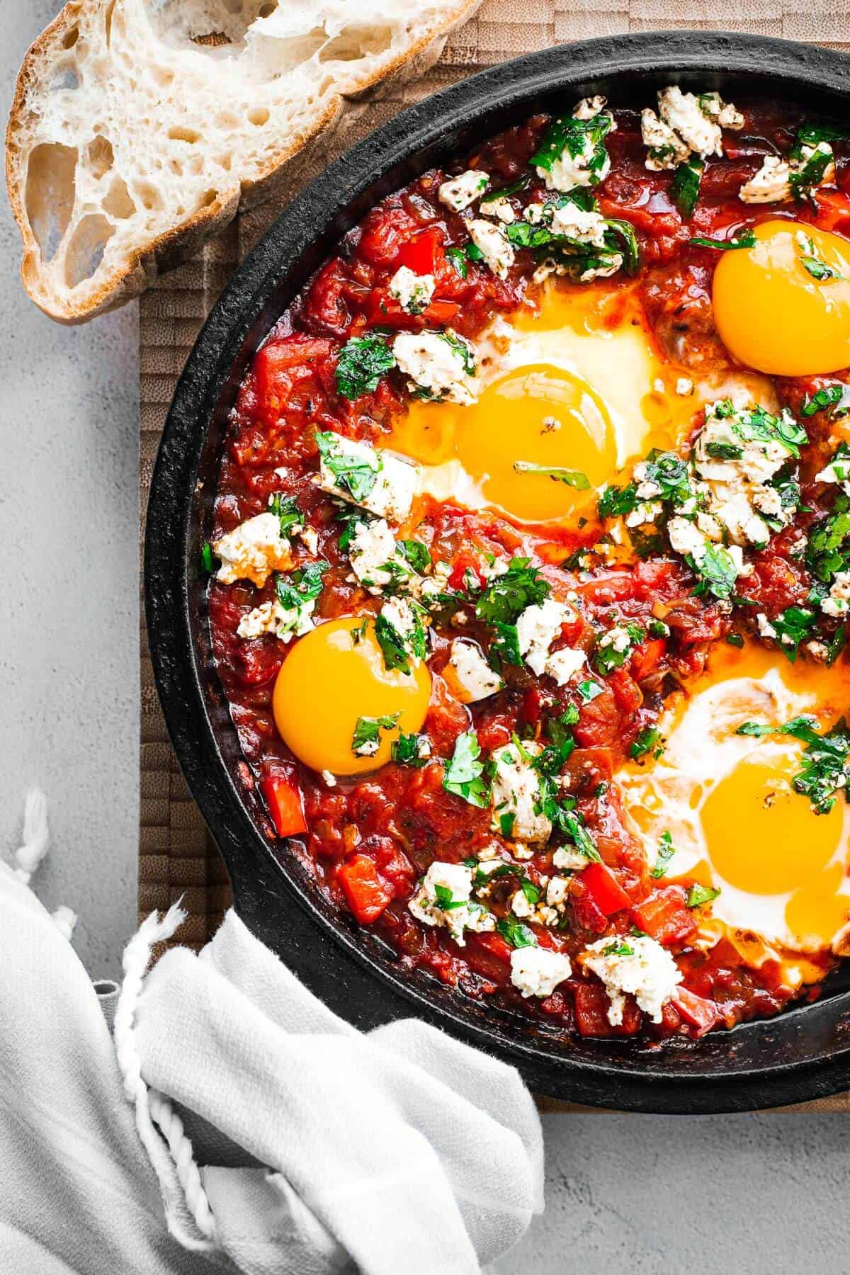 shashuka with eggs and feta in a cast iron skillet.