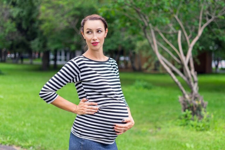 woman in stripe shirt on a camping trip while pregnant.