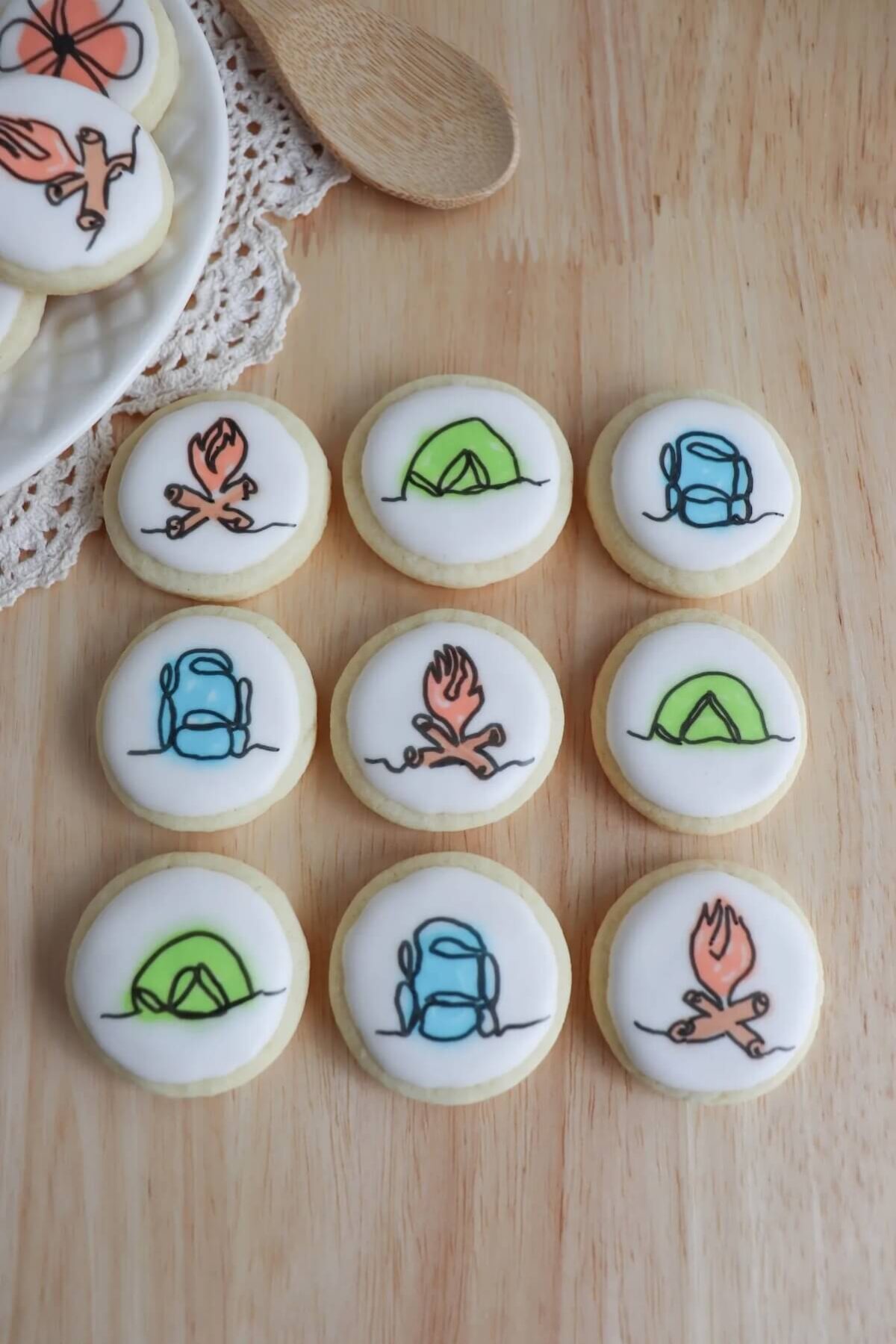 hand drawn camping sugar cookies on wooden bench.