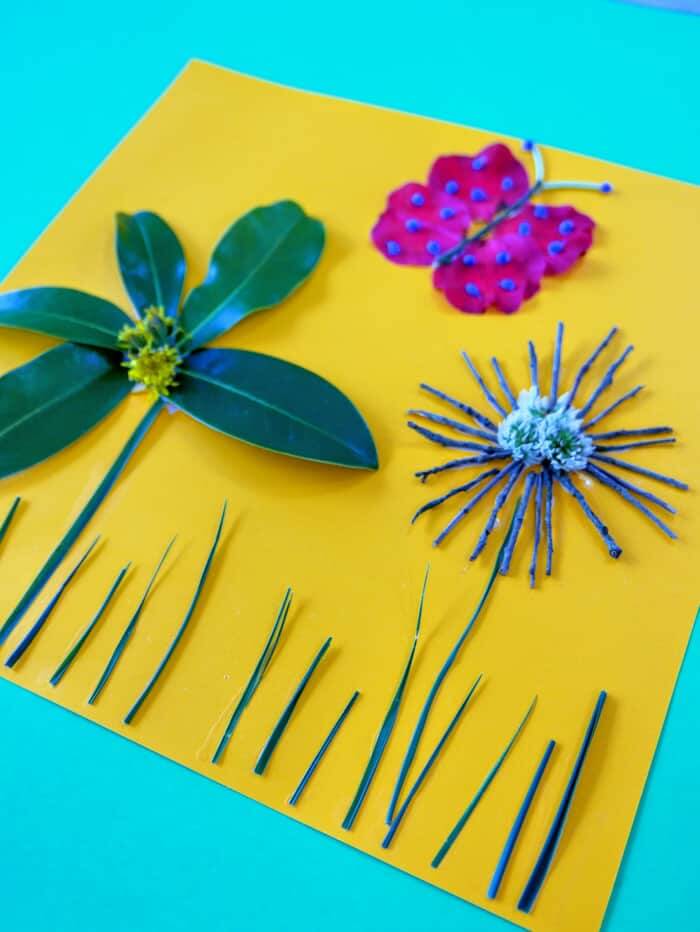 nature craft using flowers, leaves and sticks on yellow paper.