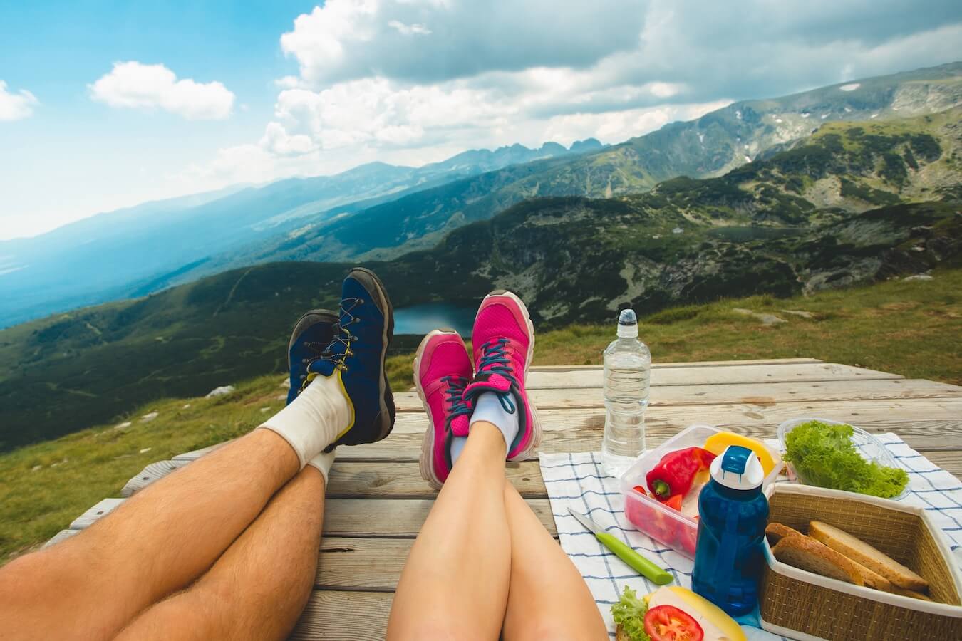 two people sitting at the top of a summit having lunch after a hike.